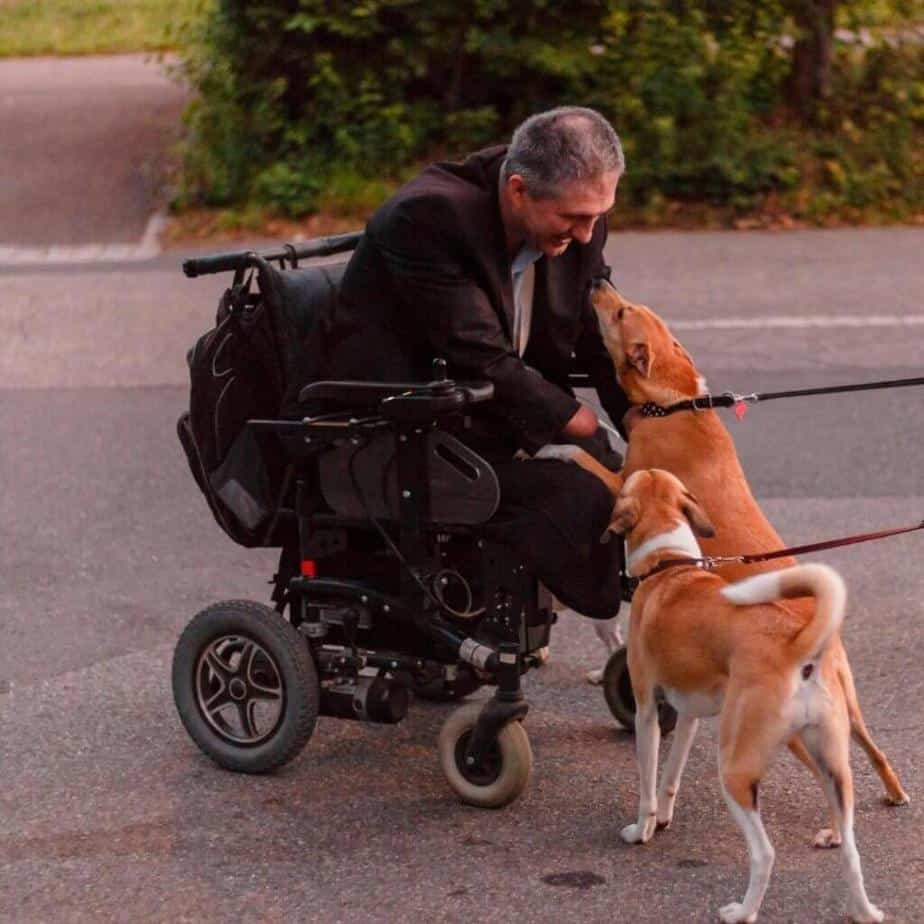  men_in_electric_wheelchair_petting_dogs.jpeg