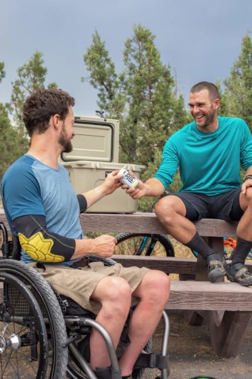 Young man in a wheelchair drinking beer with friend