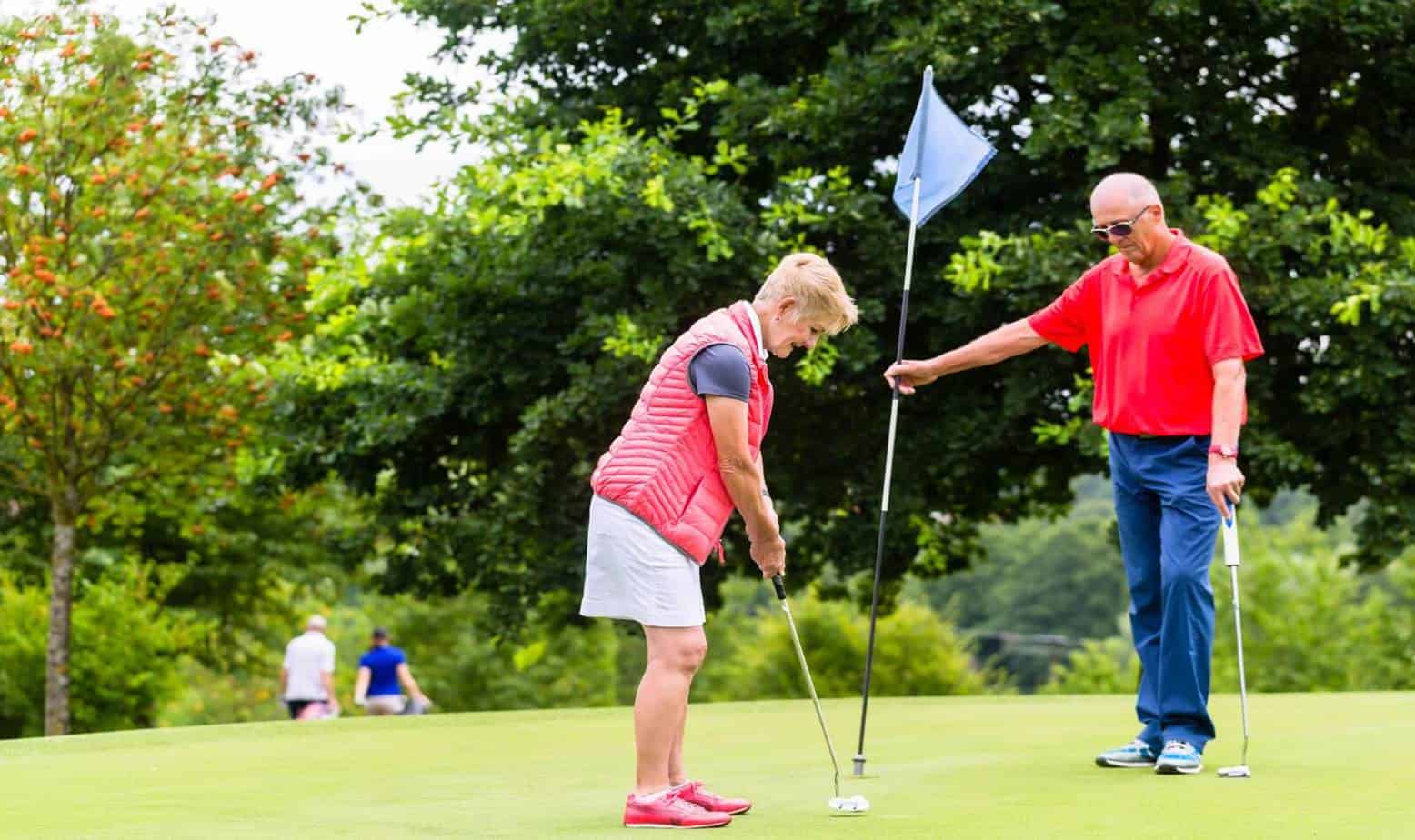 senior man and woman playing golf after performing golf stretching exercises for seniors