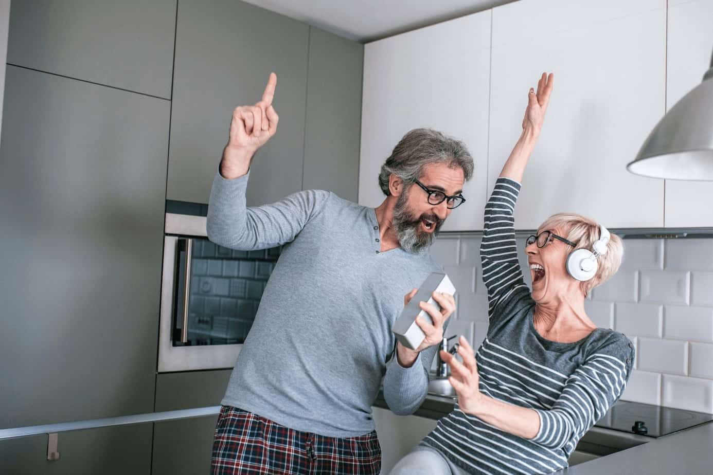 an old man and woman singing while listening to their favorite song