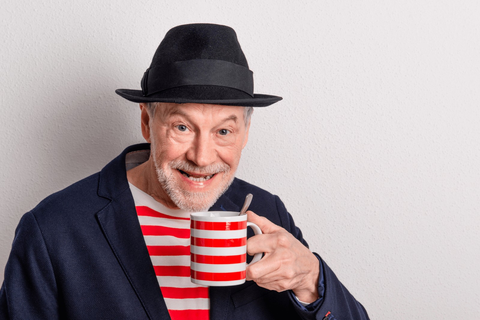 an old man wearing a striped shirt while holding a matching striped mug