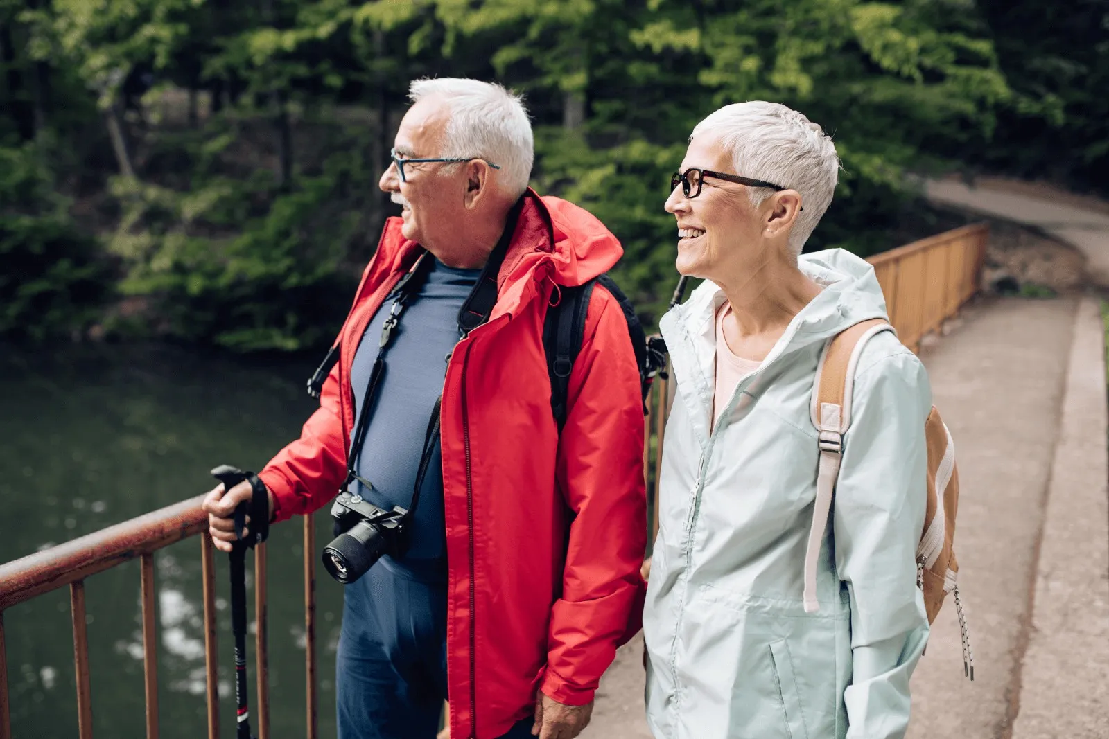 a elderly couple wearing a backpack while traveling and enjoying the lake's view