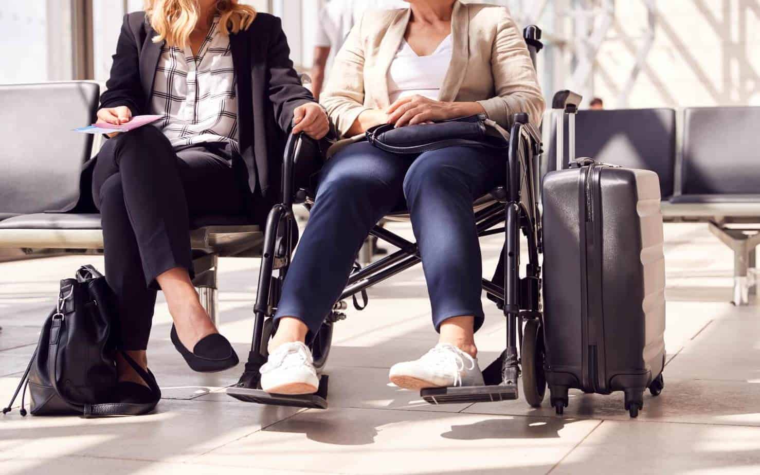 Businesswoman Sitting With Female Colleague In Wheelchair while they're in the best airlines for disabled passengers