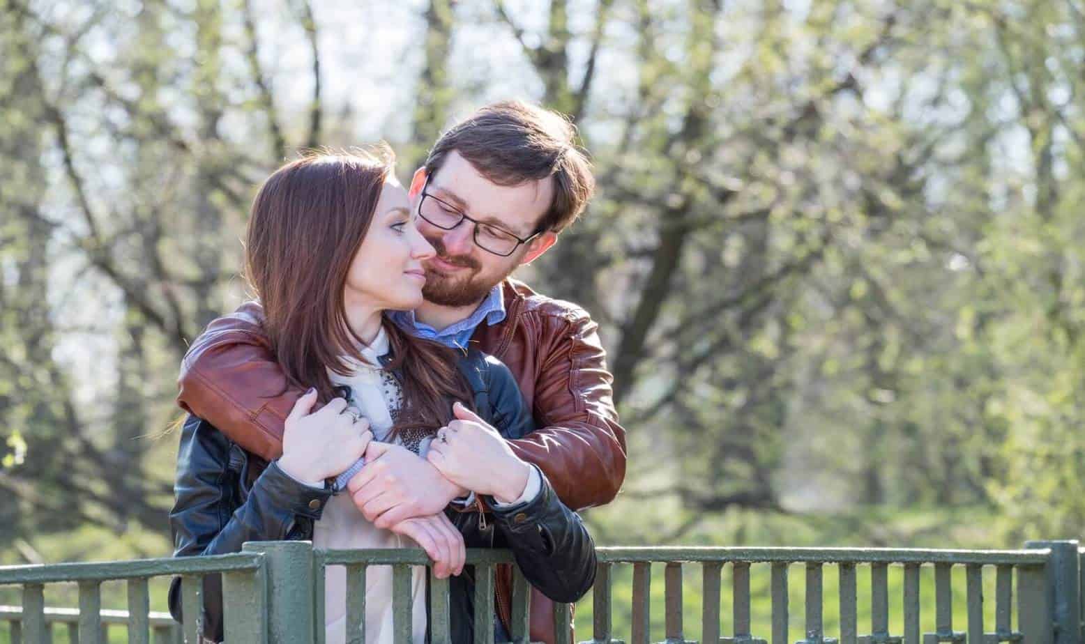 Young attractive couple on bridge in park in sunny day