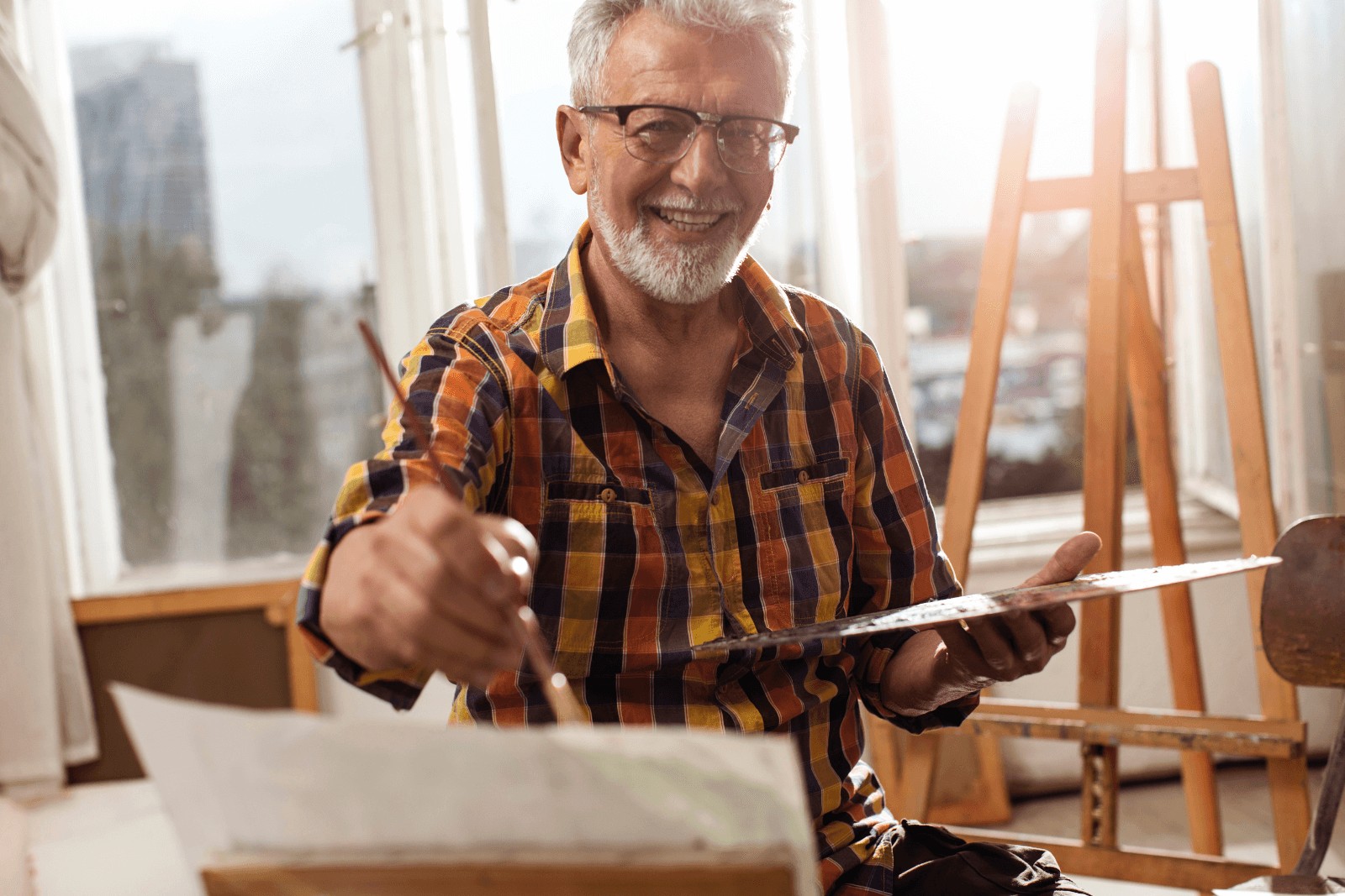 an old man painting using some paint and brushes