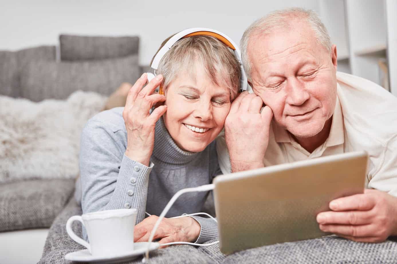 a senior couple listening to old music using a tablet and headset