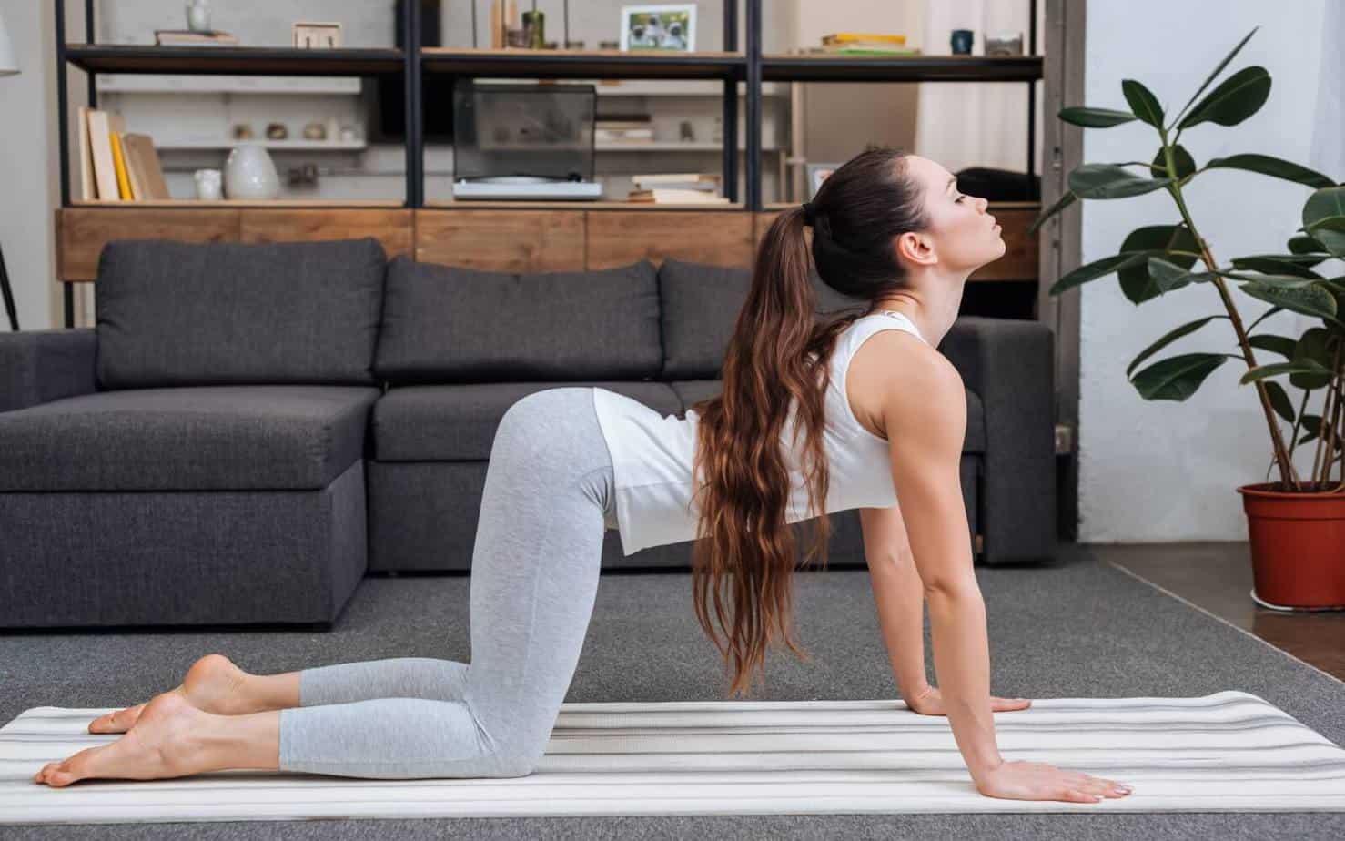 long hair lady doing cat-cow posture exercise pose in her living room