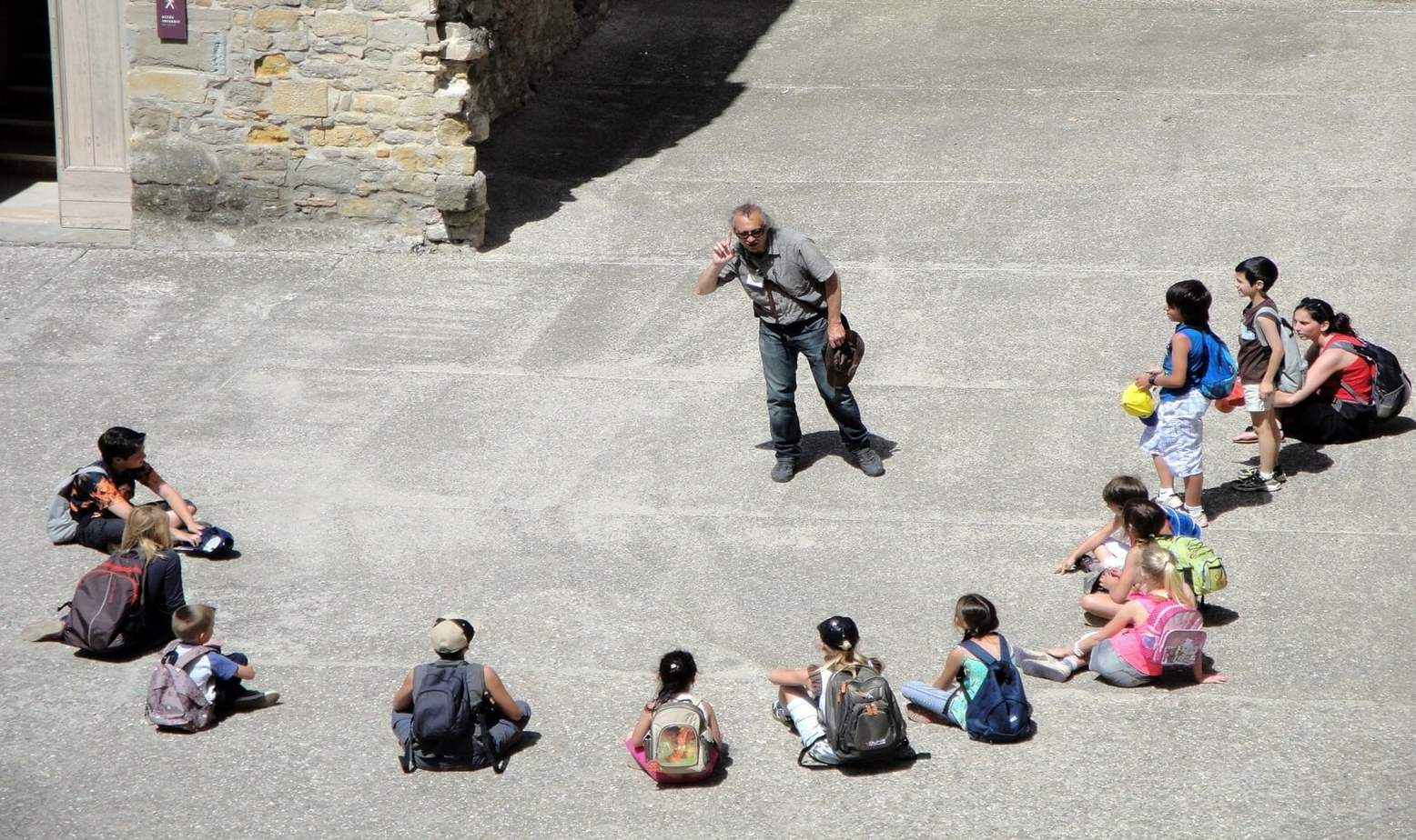 old man surrounded by the kids in the school while he is volunteering