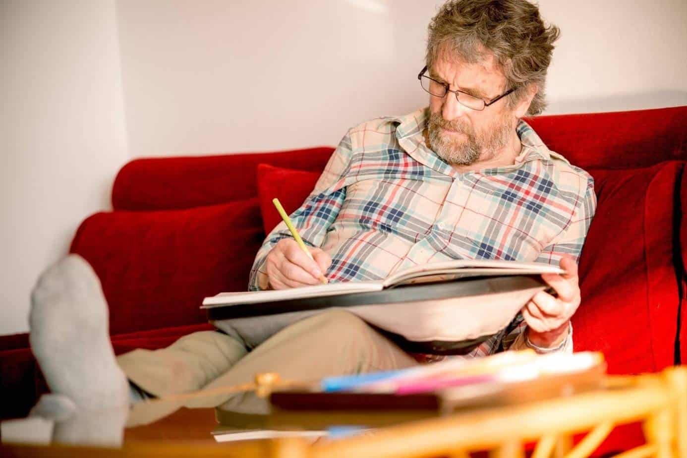 senior man relaxing on the sofa while coloring books for senior