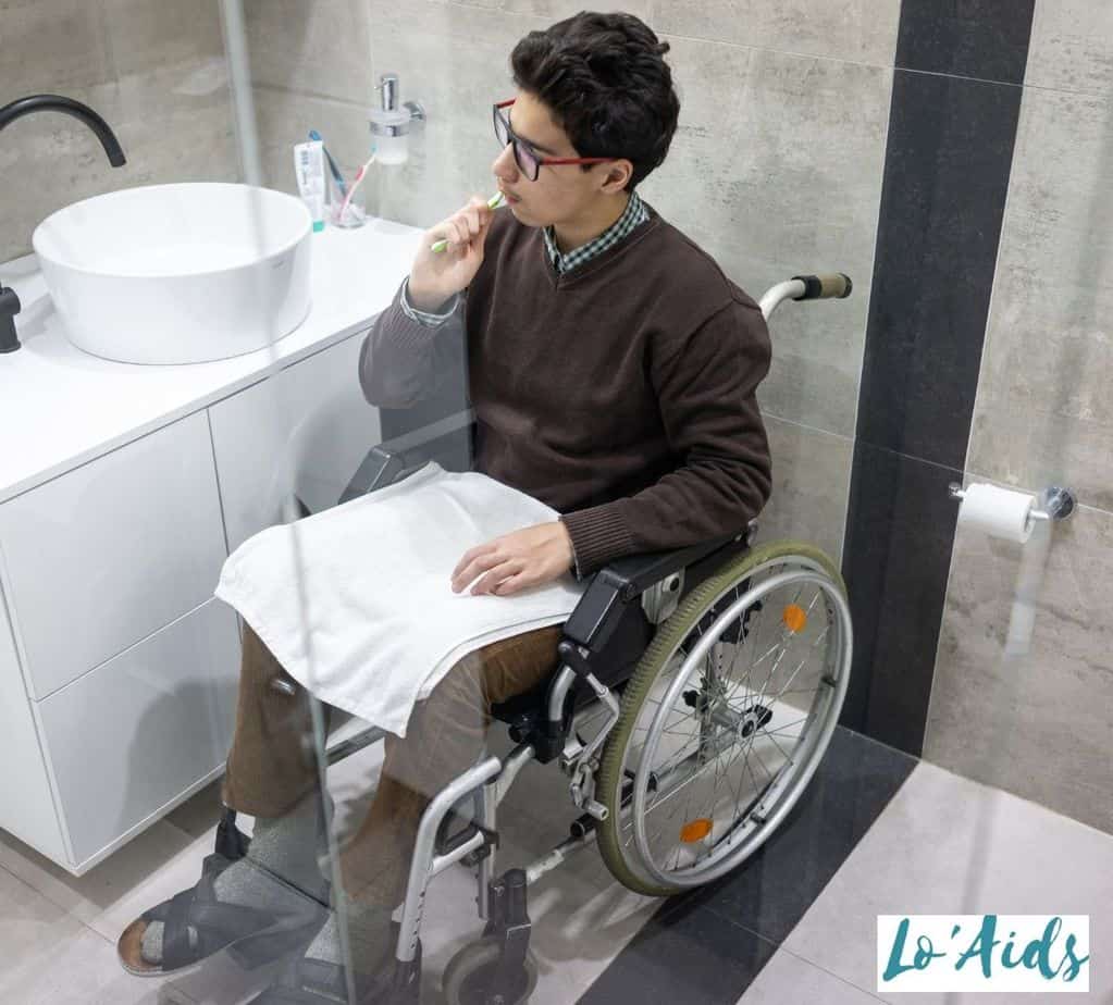 the man in a wheelchair is brushing his teeth beside the sink