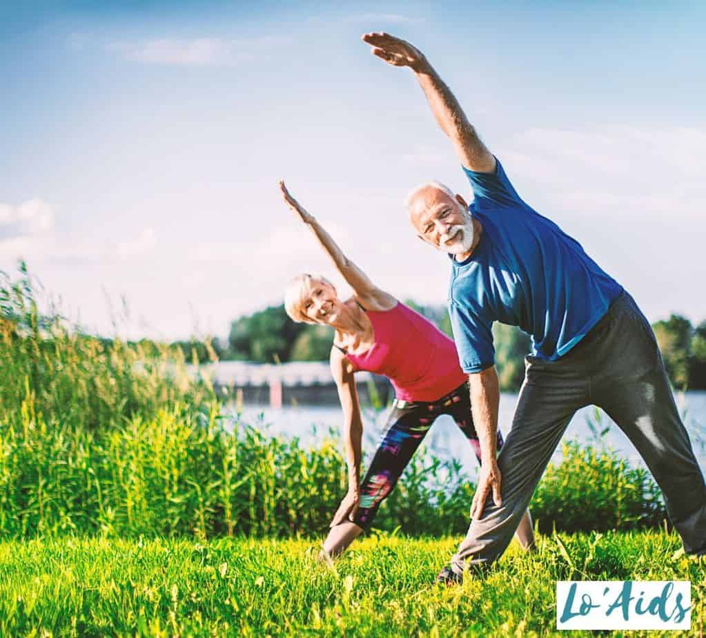 two lovely senior couple exercising beside a lake