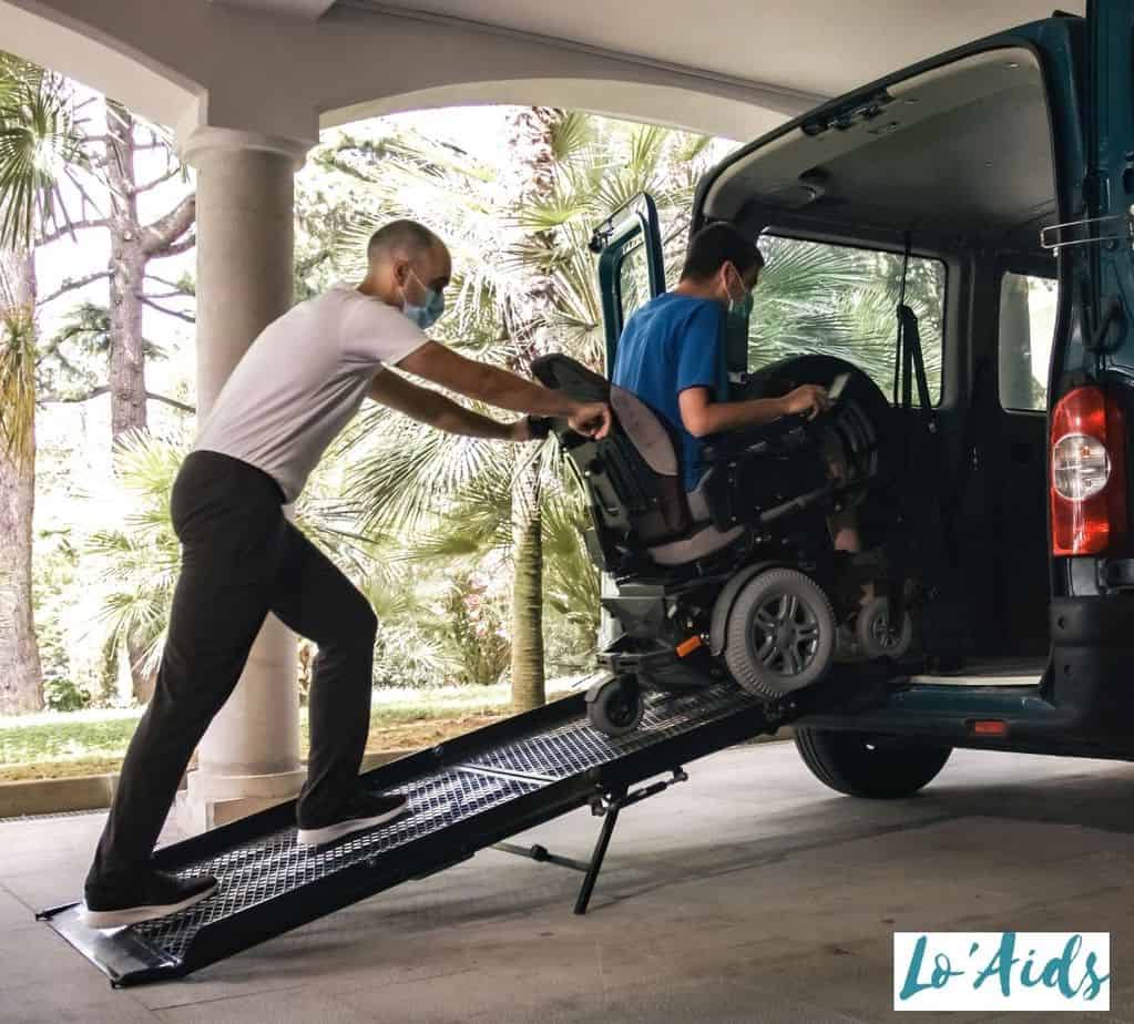 a man pushing the patient in a wheelchair inside the van through a wheelchair ramp