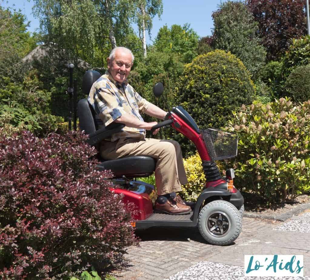 an elderly man riding a mobility scooter at the park