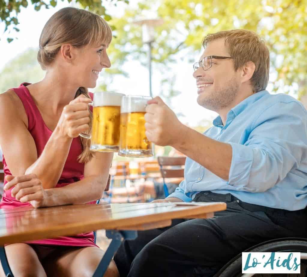 man in a wheelchair drinking beer with a pretty woman