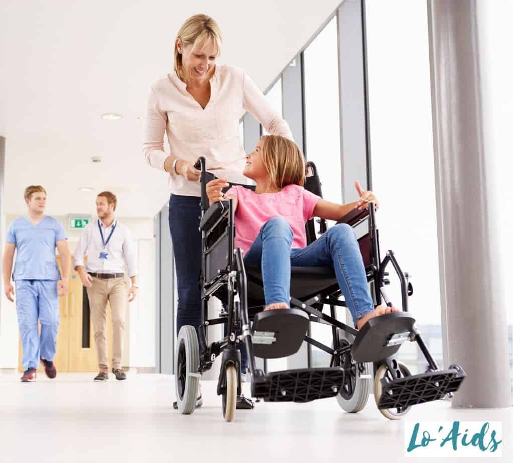 a mom pushing the transport wheelchair with her daughter