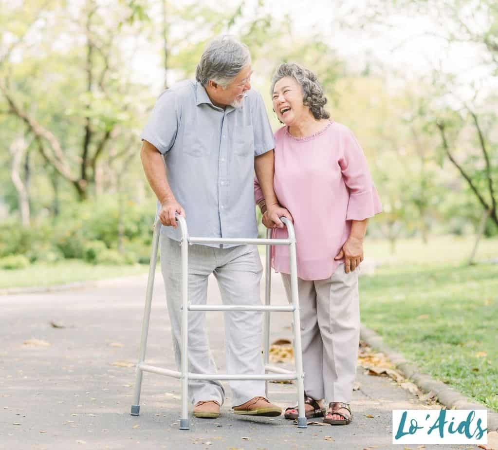 senior couple having a walk at the park. the man using a walker