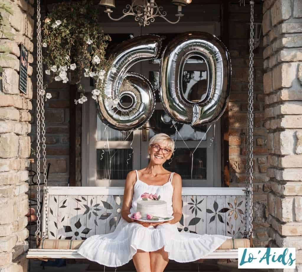 lady in white holding a birthday cake in photoshoot under title 60TH BIRTHDAY IDEAS