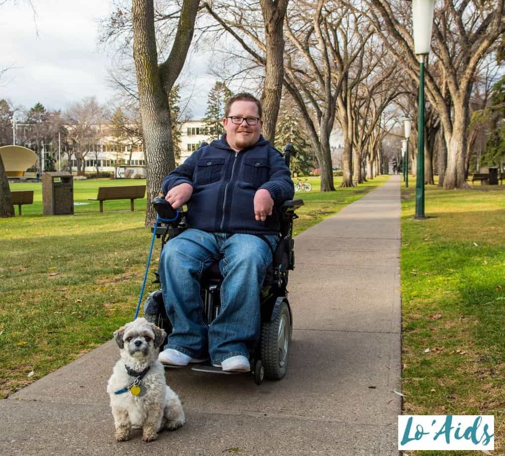 man in his power chair walking his dog at the park