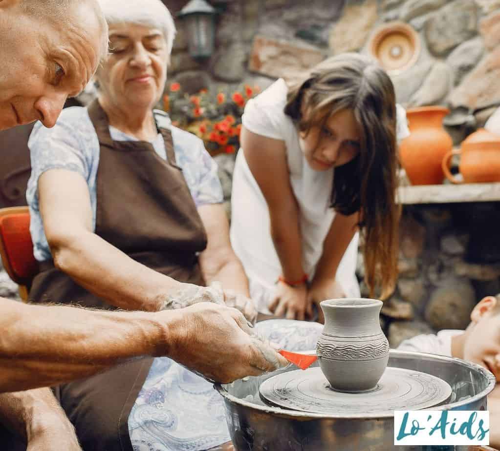 two elderly men and a young girl doing clay modelling to improve dexterity for Parkinson patients