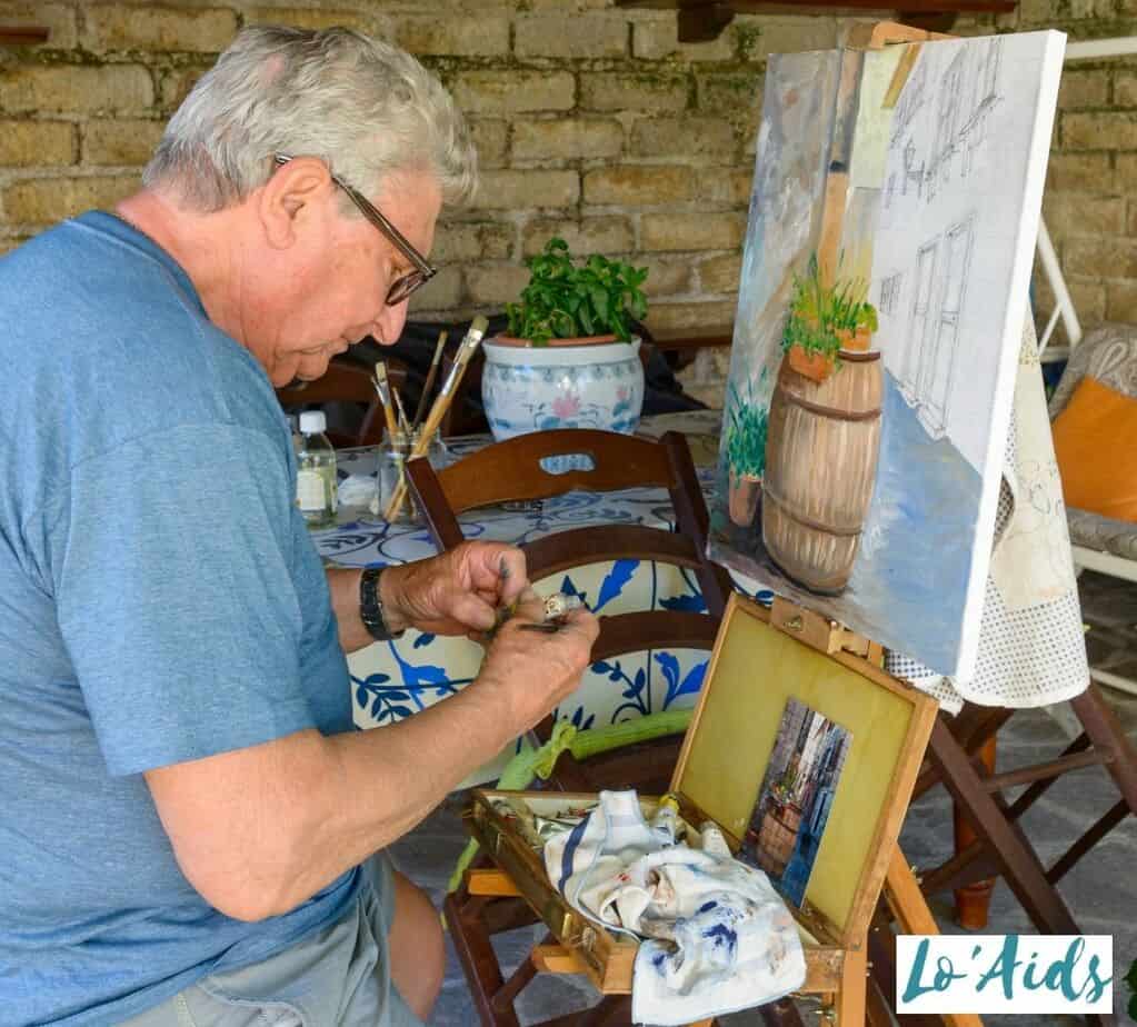 an elderly man doing an intricate painting 