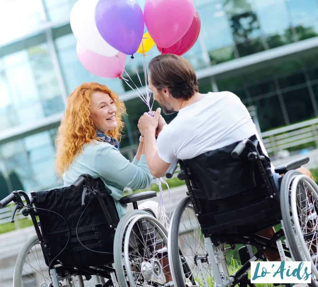 couple in a wheelchair holding balloons