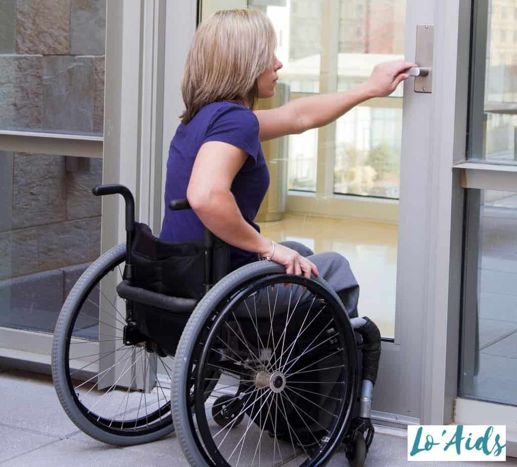 women in wheelchair opening door