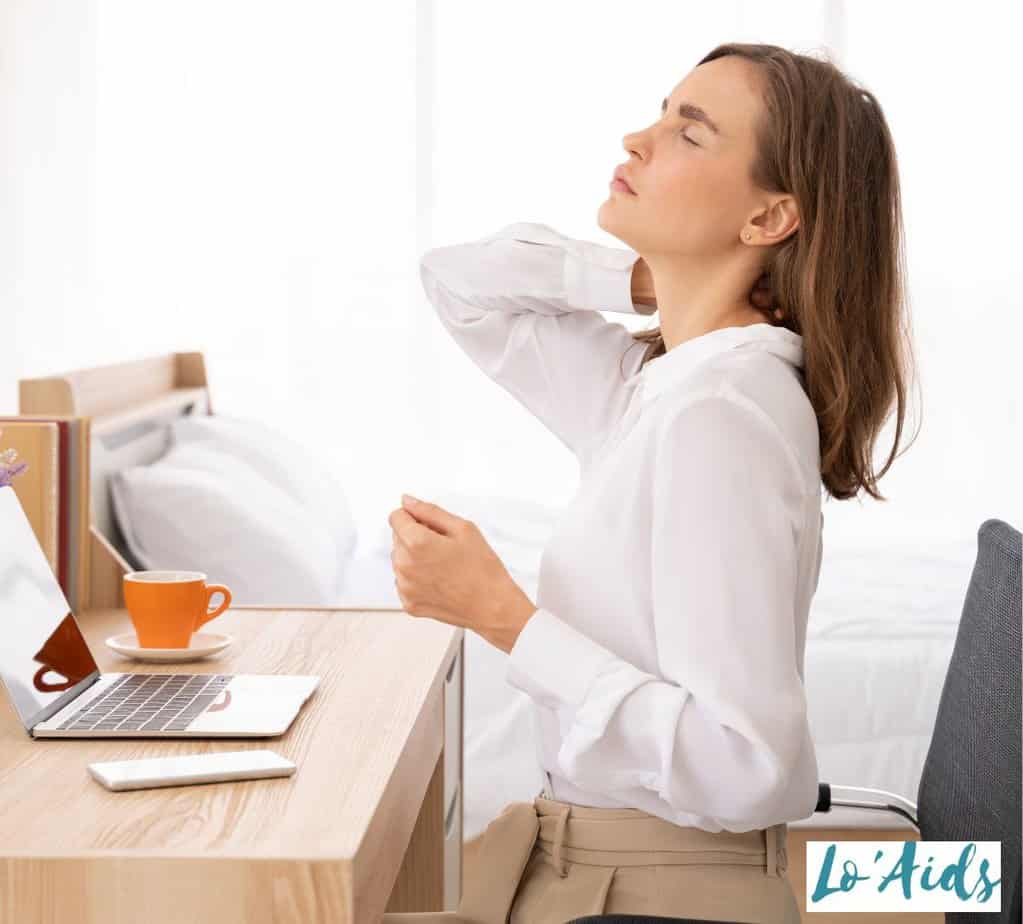 WOMAN WITH BACK PAIN SITTING ON THE CHAIR